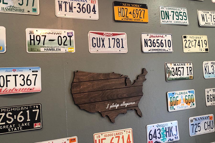 Granite City, IL Insurance - A Gray-Green Wall With a Dark Wood Cutout of the United States, Surrounded by License Plates